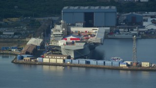AX111_056E - 5.5K aerial stock footage of an aircraft carrier at Rosyth Dockyard on Firth of Forth, Scotland