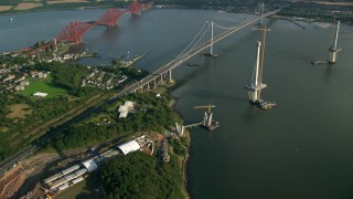 AX111_065 - 5.5K aerial stock footage of new bridge construction by Forth Road Bridge on the Firth of Forth, Scotland