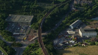 AX111_066E - 5.5K aerial stock footage of tracking a commuter train beside a highway, North Queensferry, Scotland