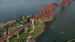 AX111_074 - 5.5K aerial stock footage of a commuter train on Forth Bridge over Firth of Forth, Scotland