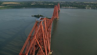 AX111_076 - 5.5K aerial stock footage of tracking a commuter train on Forth Bridge over Firth of Forth, Scotland