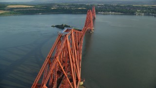 AX111_076E - 5.5K aerial stock footage of tracking a commuter train on Forth Bridge over Firth of Forth, Scotland