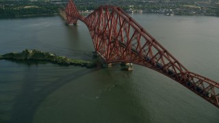 AX111_077 - 5.5K aerial stock footage of tracking a commuter train on Forth Bridge spanning Firth of Forth, Scotland