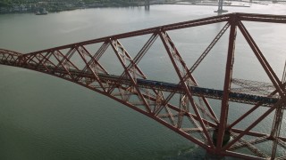 AX111_078 - 5.5K aerial stock footage of tracking a commuter train on Forth Bridge over Firth of Forth, Scotland