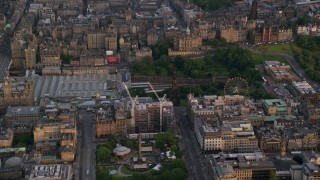 AX112_013 - 5.5K aerial stock footage of Scott Monument, St Andrew Square, and train station, Edinburgh, Scotland at sunset