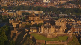 AX112_034E - 5.5K aerial stock footage of flying by the hilltop Edinburgh Castle, Scotland at sunset