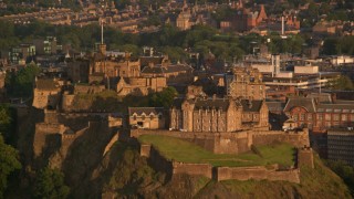 AX112_035 - 5.5K aerial stock footage of flying by the hilltop Edinburgh Castle, Scotland at sunset