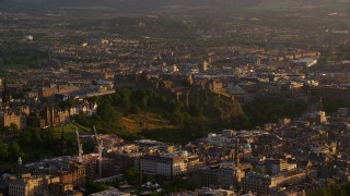 AX112_042E - 5.5K aerial stock footage of Edinburgh Castle on a hilltop in Scotland at sunset