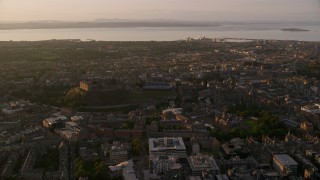 AX112_049 - 5.5K aerial stock footage of flying by historic Edinburgh Castle and the cityscape, Scotland at sunset