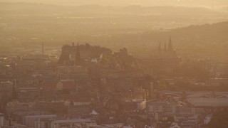 AX112_065E - 5.5K aerial stock footage of iconic Edinburgh Castle and Arthur's Seat, Scotland during hazy sunset