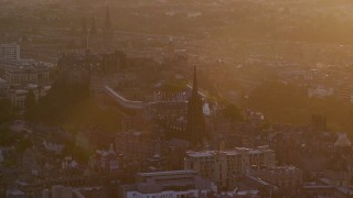 AX112_075E - 5.5K aerial stock footage of passing iconic Edinburgh Castle and The Hub cathedral, Scotland at sunset