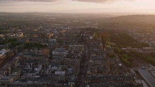 AX112_095 - 5.5K aerial stock footage fly over Canongate to approach historic Edinburgh Castle, Scotland at sunset