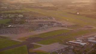 AX112_116E - 5.5K aerial stock footage of terminals and control tower of Edinburgh Airport, Scotland at sunset