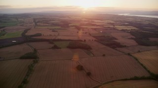 AX112_128E - 5.5K aerial stock footage of farm fields with the sun setting, Broxburn, Scotland