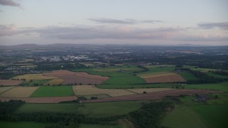 AX112_131E - 5.5K aerial stock footage of passing by farm fields at sunset in Broxburn, Scotland