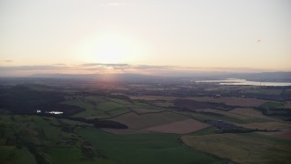 AX112_133E - 5.5K aerial stock footage pan across farming fields at sunset in Linlithgow, Scotland