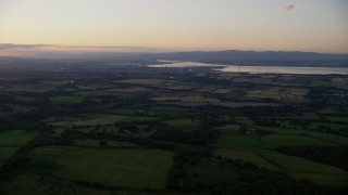 AX112_138 - 5.5K aerial stock footage of farmland near a power plant, Falkirk, Scotland at twilight