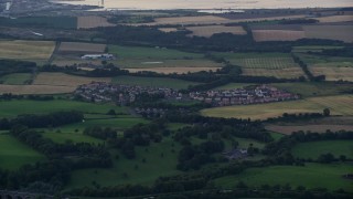 AX112_139 - 5.5K aerial stock footage of farmland and rural homes in a village near Falkirk, Scotland at twilight