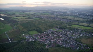 AX112_146E - 5.5K aerial stock footage of orbiting rural homes in small village near Falkirk, Scotland at twilight