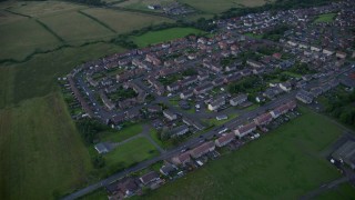 AX112_148 - 5.5K aerial stock footage of orbiting rural village homes and farmland, Shieldhill, Scotland at twilight