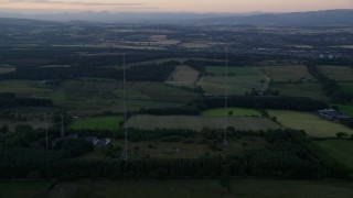 AX112_150 - 5.5K aerial stock footage orbit radio towers by farmland, Falkirk, Scotland at sunset