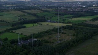 AX112_151 - 5.5K aerial stock footage of orbiting radio towers surrounded by farmland, Falkirk, Scotland at twilight