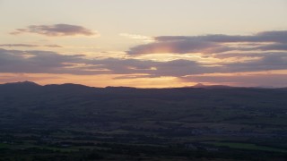 AX112_152E - 5.5K aerial stock footage of setting sun behind clouds over Scottish Highlands, Scotland