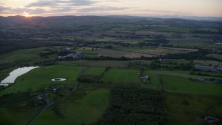 AX112_156 - 5.5K aerial stock footage of passing by farms and farm fields at sunset in Bonnybridge, Scotland