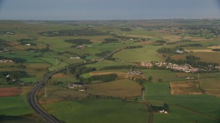 AX113_004E - 5.5K aerial stock footage of farms, fields and rural homes near A726 Highway, Glasgow, Scotland at sunrise