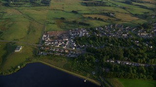 AX113_009 - 5.5K aerial stock footage of orbiting homes in the village of Eaglesham, Scotland at sunrise