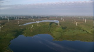 AX113_011 - 5.5K stock footage aerial video approach windmills and fly over reservoirs, Eaglesham, Scotland at sunrise