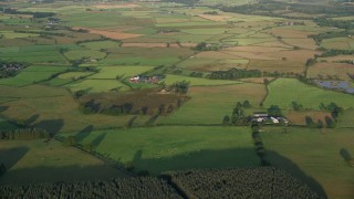AX113_024E - 5.5K aerial stock footage of farm fields and rural homes, Kilmarnock, Scotland at sunrise