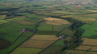 AX113_026E - 5.5K aerial stock footage approach and fly over farms and fields in Kilmarnock, Scotland at sunrise