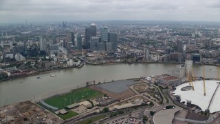 AX114_139E - 5.5K aerial stock footage orbit The O2 arena, with Canary Wharf skyscrapers in background, London, England