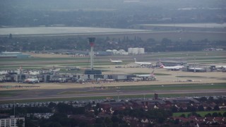 AX114_286E - 5.5K aerial stock footage of the control tower and airliner at London Heathrow Airport, England