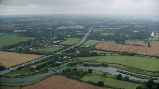 AX114_326E - 5.5K aerial stock footage of an orbit of M4 freeway and farmland near Bray Lake, Maidenhead, England Day