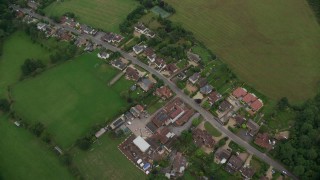 AX114_338 - 5.5K aerial stock footage of tilting to a bird's eye view of rural homes and farm fields, Windsor, England