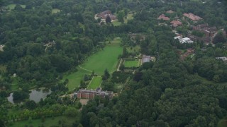 AX114_342E - 5.5K aerial stock footage of an orbit of upscale homes surrounded by trees, Ascot, England