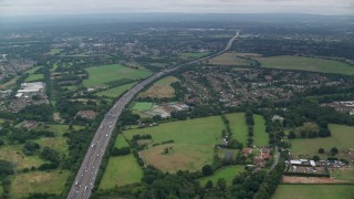 AX114_352E - 5.5K aerial stock footage approach M25 Freeway from neighborhoods, Chertsey, England