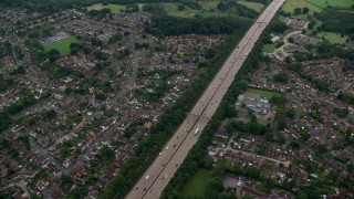 AX114_355E - 5.5K aerial stock footage of flying over M25 Freeway past farm fields, Addlestone, England