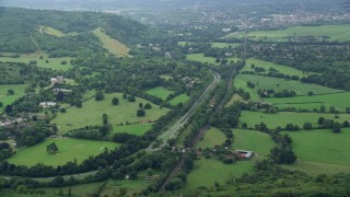AX114_372E - 5.5K aerial stock footage of a country road and farming fields with trees, Leatherhead, England