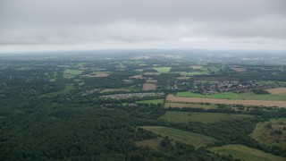 AX114_376E - 5.5K aerial stock footage fly over rural homes and approach farm fields, Tadworth, England