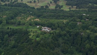 AX114_384 - 5.5K aerial stock footage of approach and title down on a large rural home among the trees, Redhill, England