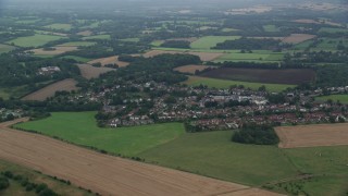 AX114_385 - 5.5K aerial stock footage of passing by a farmland community, Redhill, England
