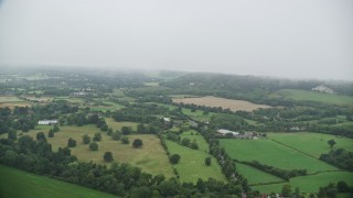 AX115_003E - 5.5K aerial stock footage of flying through low clouds by farms and trees, Redhill, England