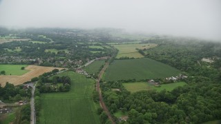 AX115_005E - 5.5K aerial stock footage approach homes by train tracks and farmland in Betchworth, England