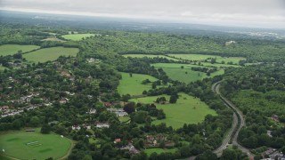 AX115_008E - 5.5K aerial stock footage of flying over freeway near village, farm fields, and forests, Dorking, England