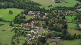 AX115_010E - 5.5K aerial stock footage approach a small village with homes by farm fields, Mickleham, England
