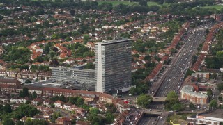 AX115_015E - 5.5K aerial stock footage of passing an office building beside residential area, Tolworth, England