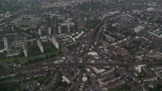 AX115_056 - 5.5K aerial stock footage fly over residential area with train tracks in the rain, London, England